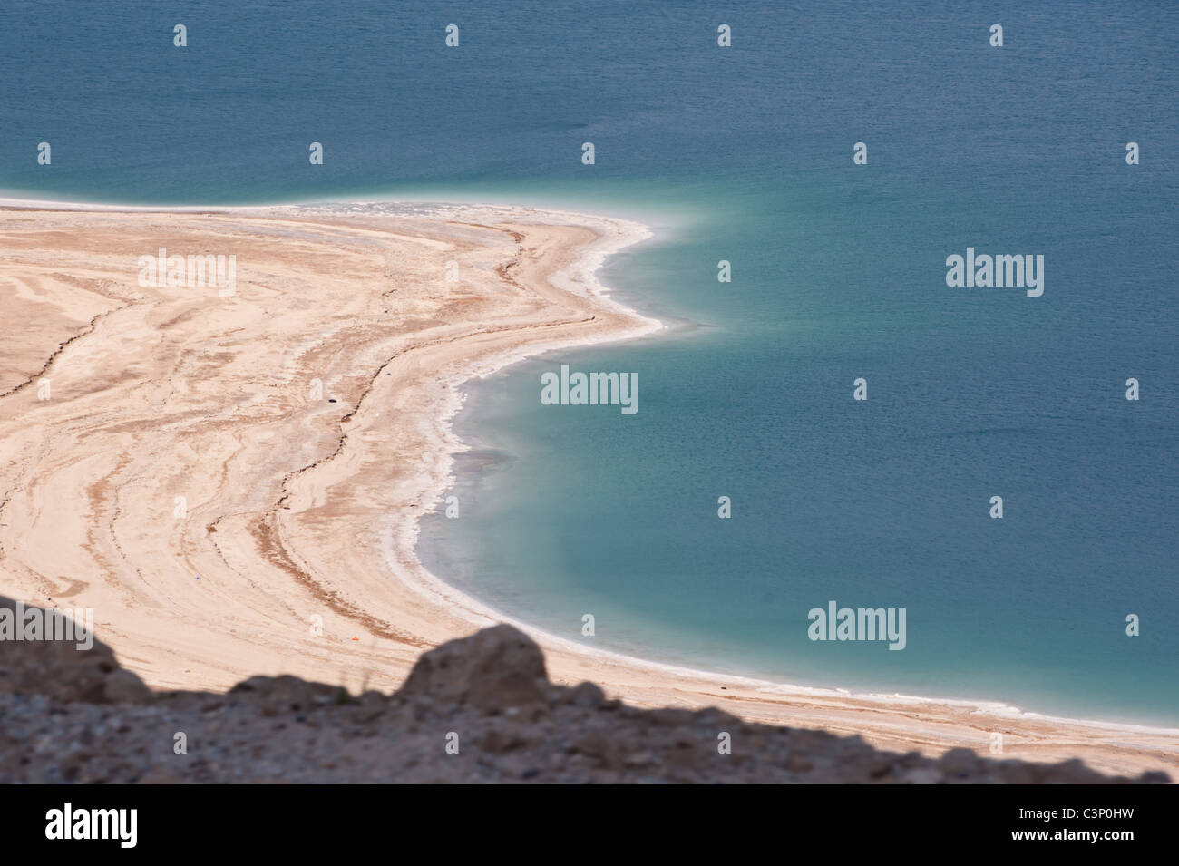 The exceptionally salty waters of the Dead Sea form encrusted layers of minerals along the shore. Stock Photo