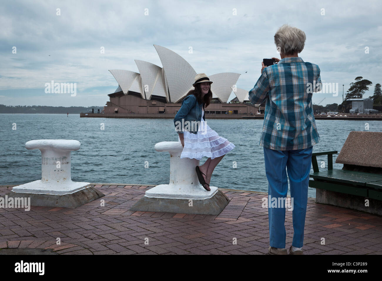 A woman photographing a girl with the Sydney Opera House as a backdrop