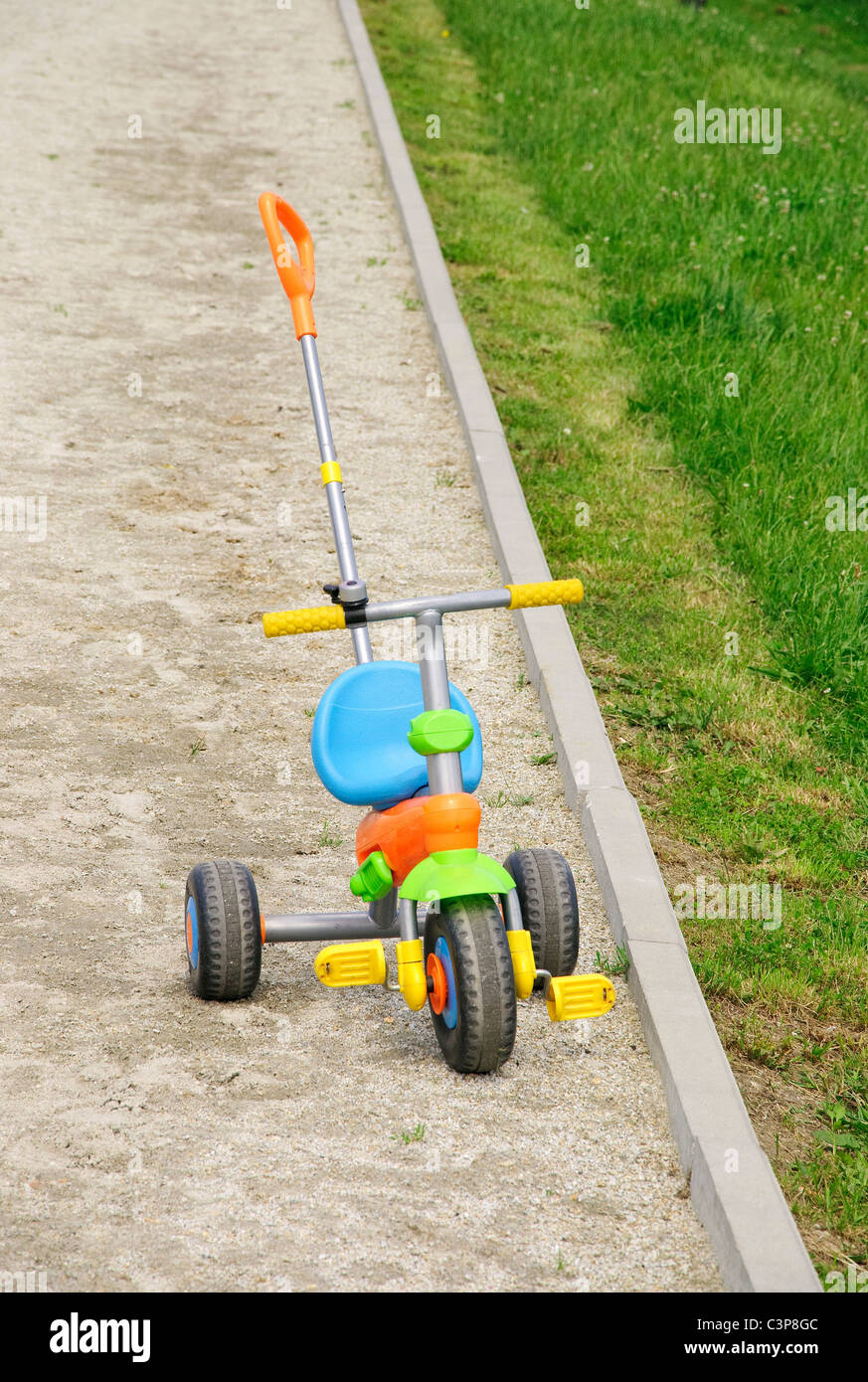 Three wheel children's bicycle left on the sand Stock Photo