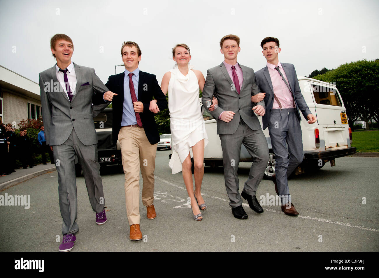 Year 11 secondary school students 'leaving' prom, UK - a girl walking arm in arm with four boys Stock Photo