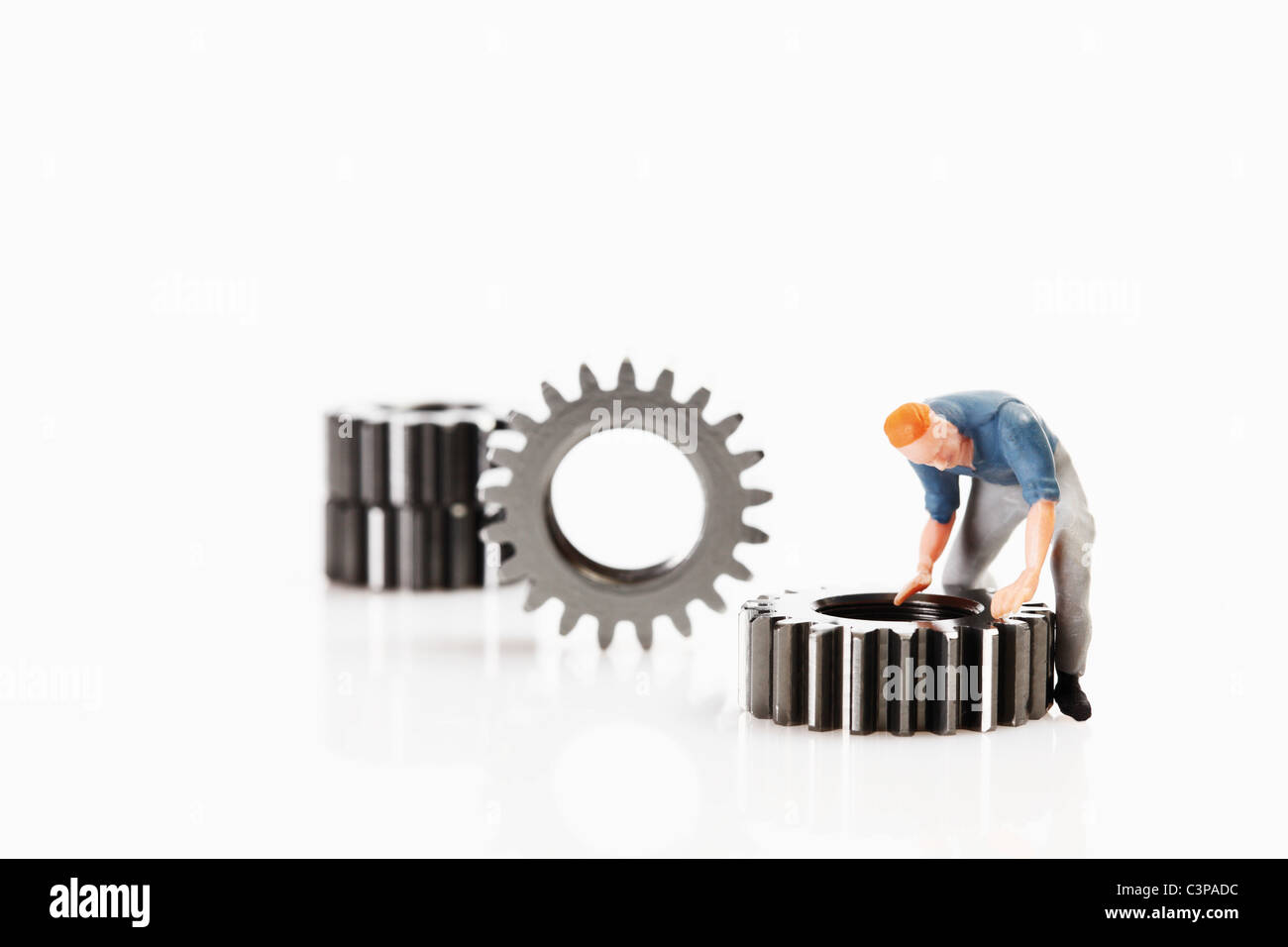 Worker figurine repairing cogwheel on white background Stock Photo