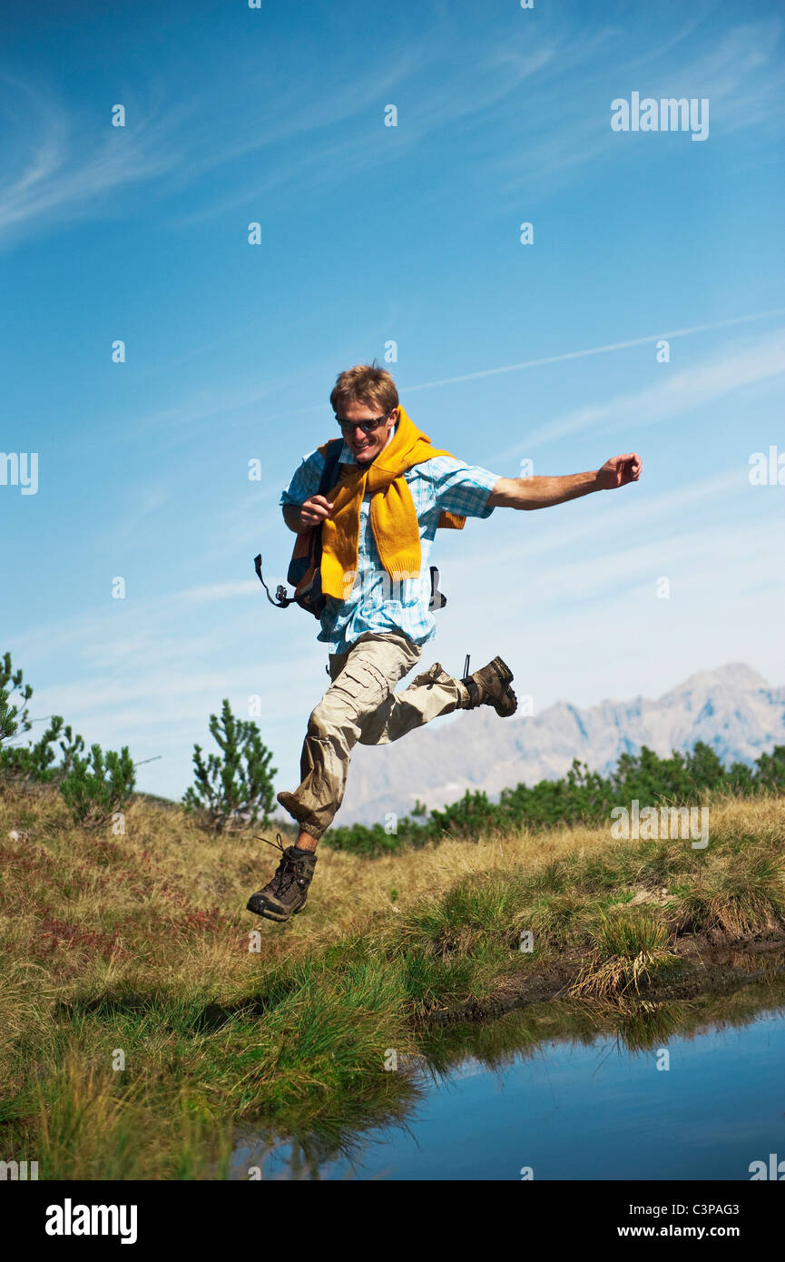 Austria, Salzburger Land, Man jumping by waterside, laughing, portrait ...