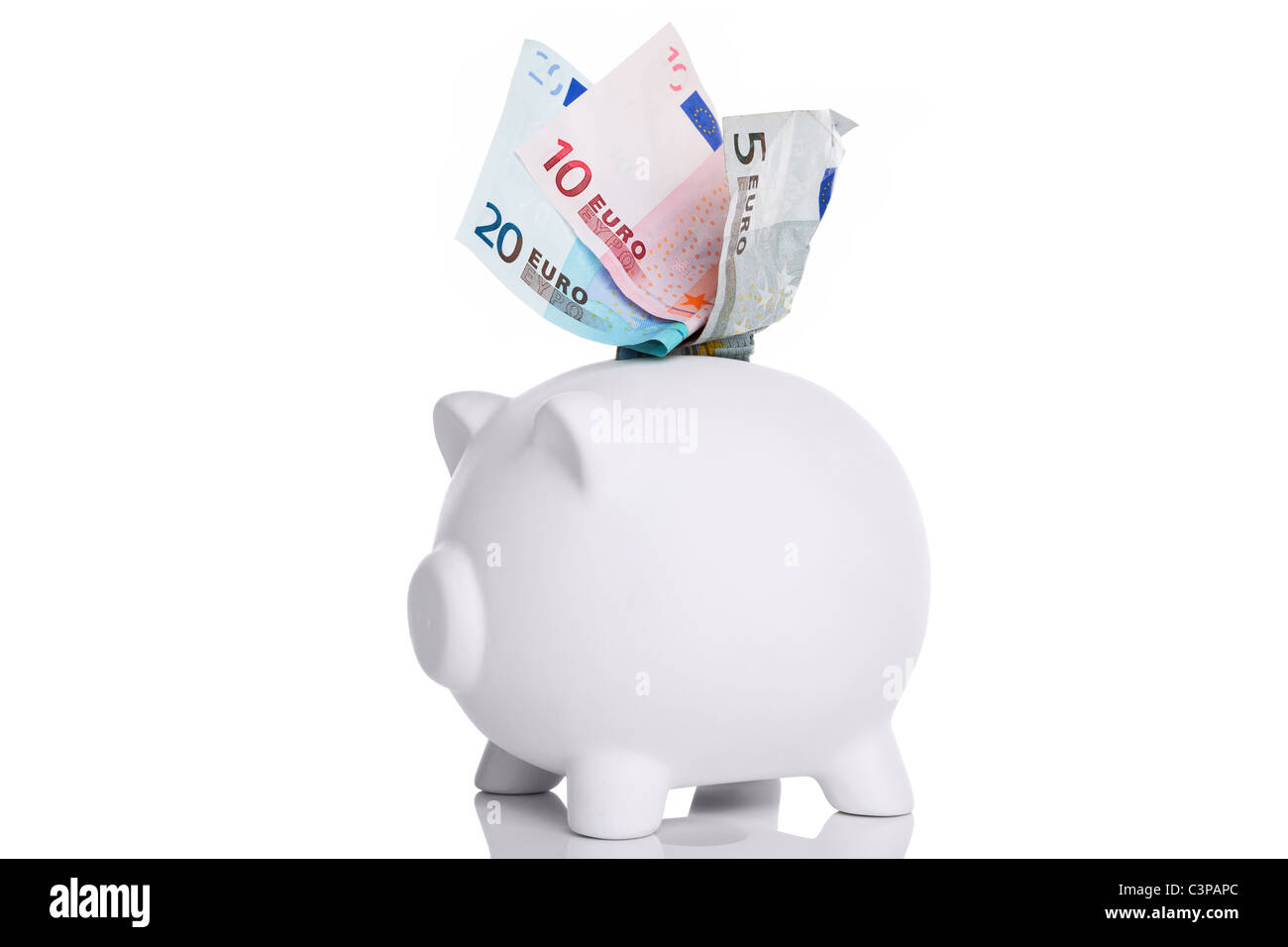 Photo of a white piggy bank with Euros in the slot cut out on a white background. Stock Photo