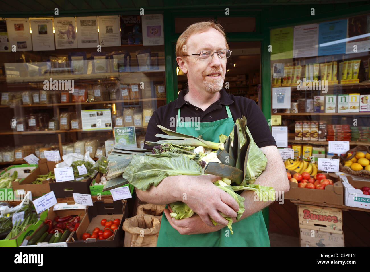 Shopkeeper outside his organic wholefoods shop in Totnes, Devon , UK. Stock Photo