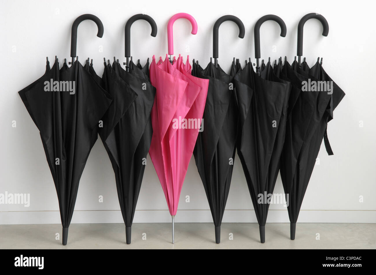 Black umbrellas with one pink umbrella Stock Photo