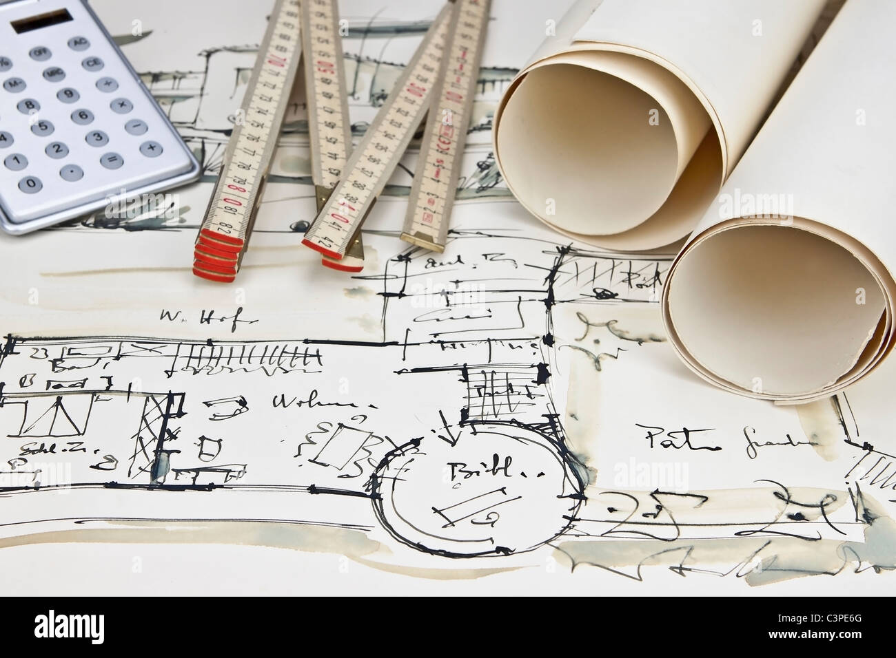 the blueprint of a house with two paper rolls, a calculator and a rule Stock Photo