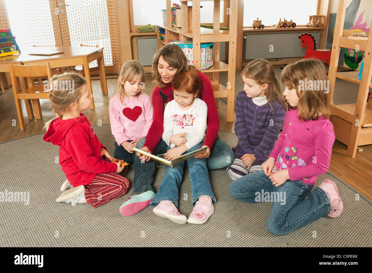 Germany, Female nursery teacher and children in nursery Stock Photo