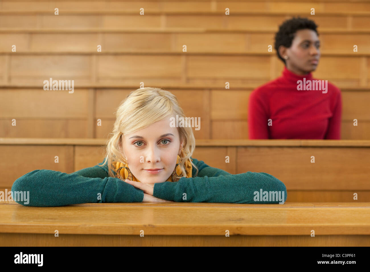 Germany, Leipzig, Student leaning on desk, woman sitting in background Stock Photo