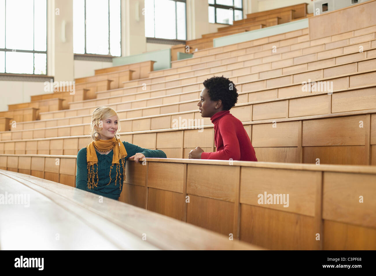Germany, Leipzig, Students sitting face to face and talking in auditorium Stock Photo