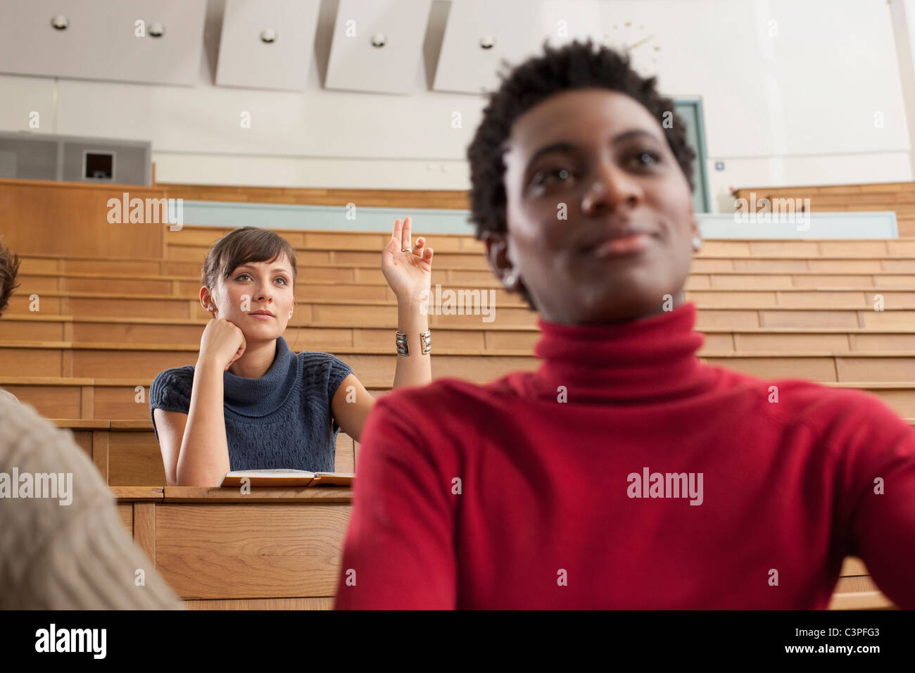 Germany, Leipzig, University student raising hand in classroom Stock Photo