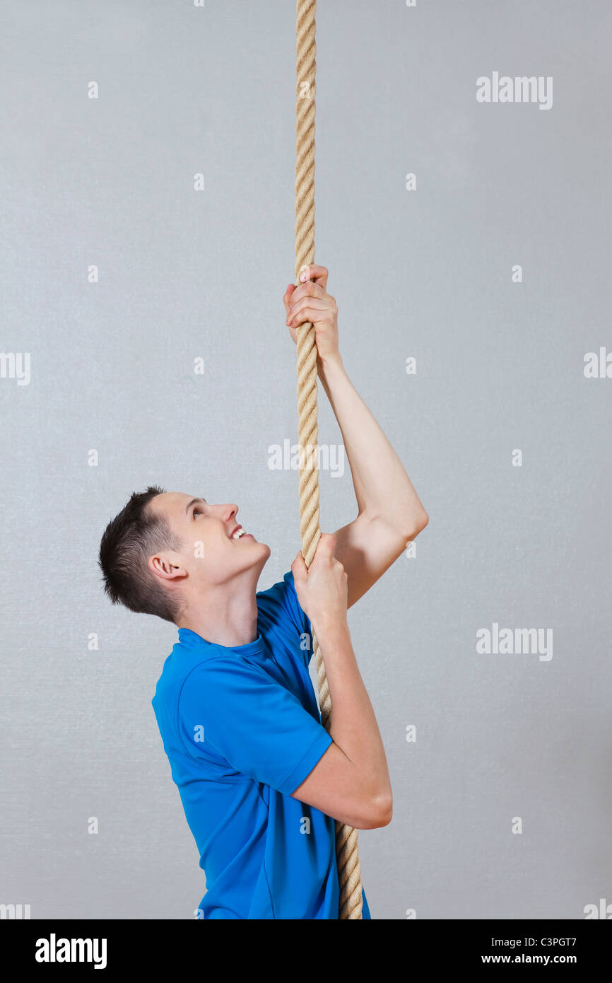 Germany, Berlin, Young man climbing rope in school gym Stock Photo - Alamy