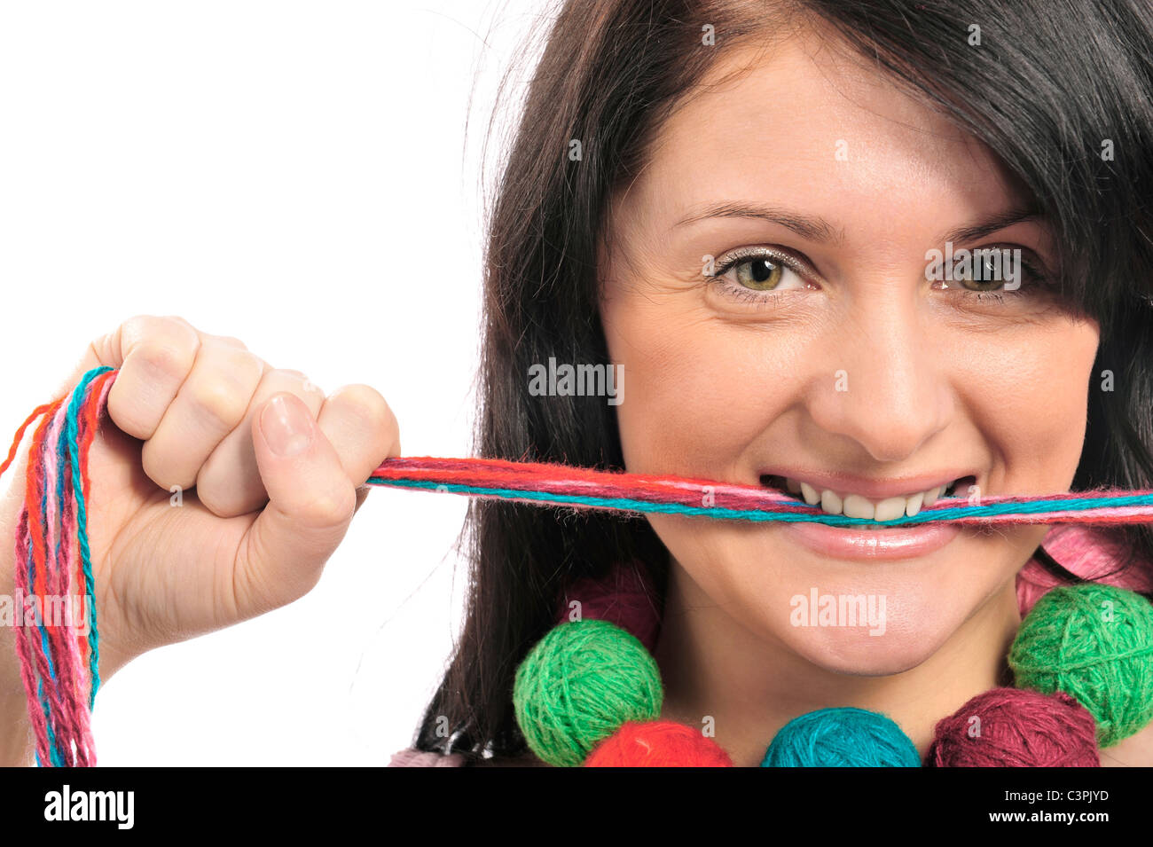 Portrait of a beautiful young girl with colored yarn in her mouth. Isolated white background. Stock Photo