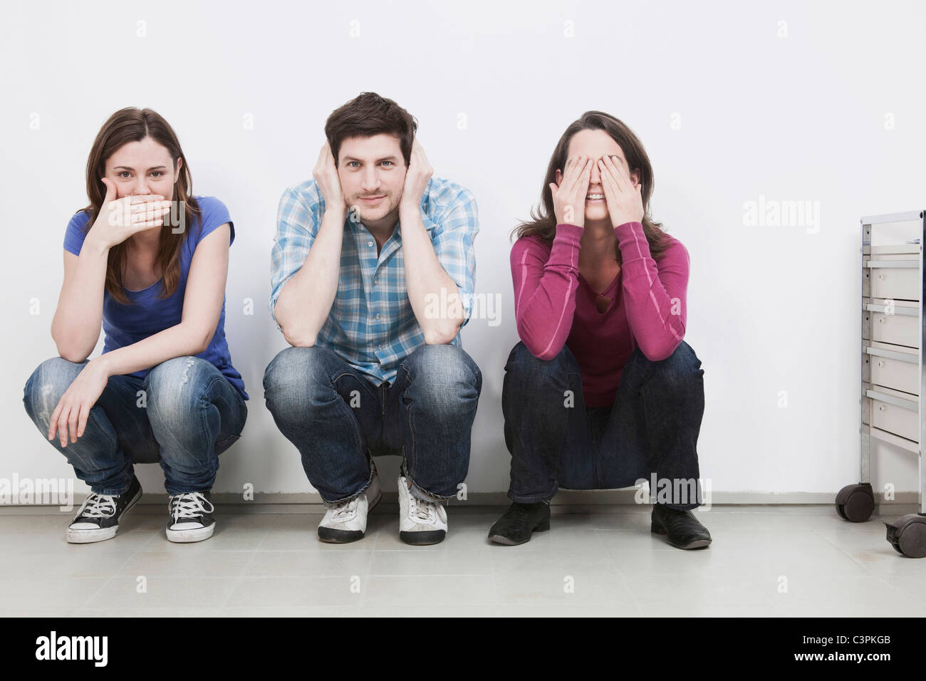 Men and women crouching, covering eyes, ears and mouth Stock Photo Alamy