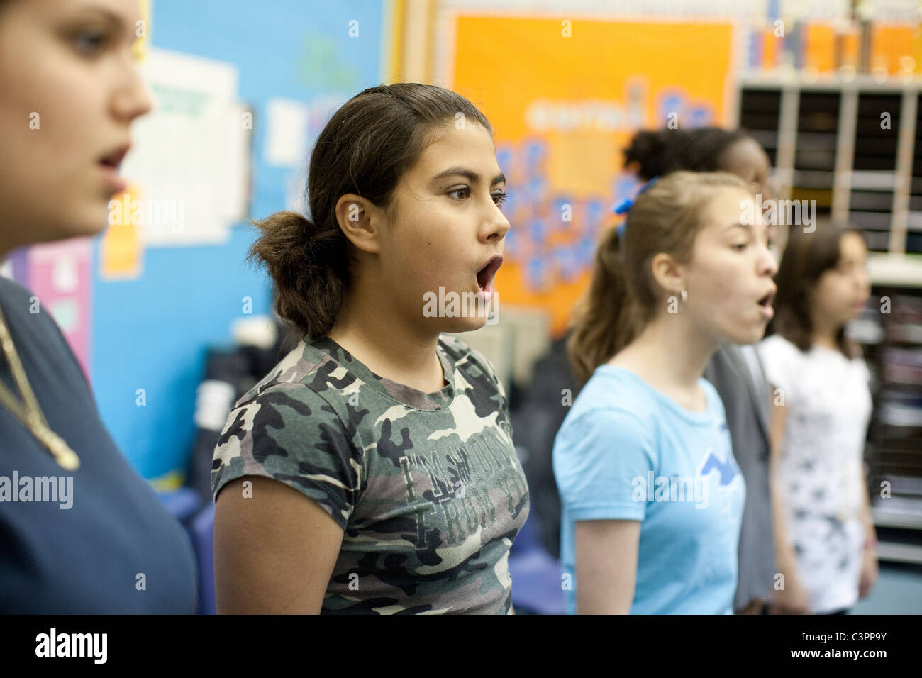 Multiethnic group of female students sing during choir class at junior