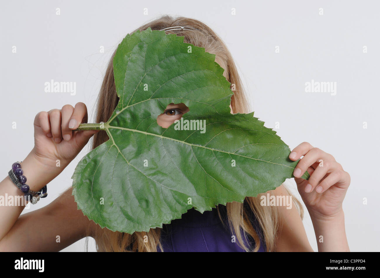 Girl (10-11 Years) holding leaf in front of face Stock Photo - Alamy