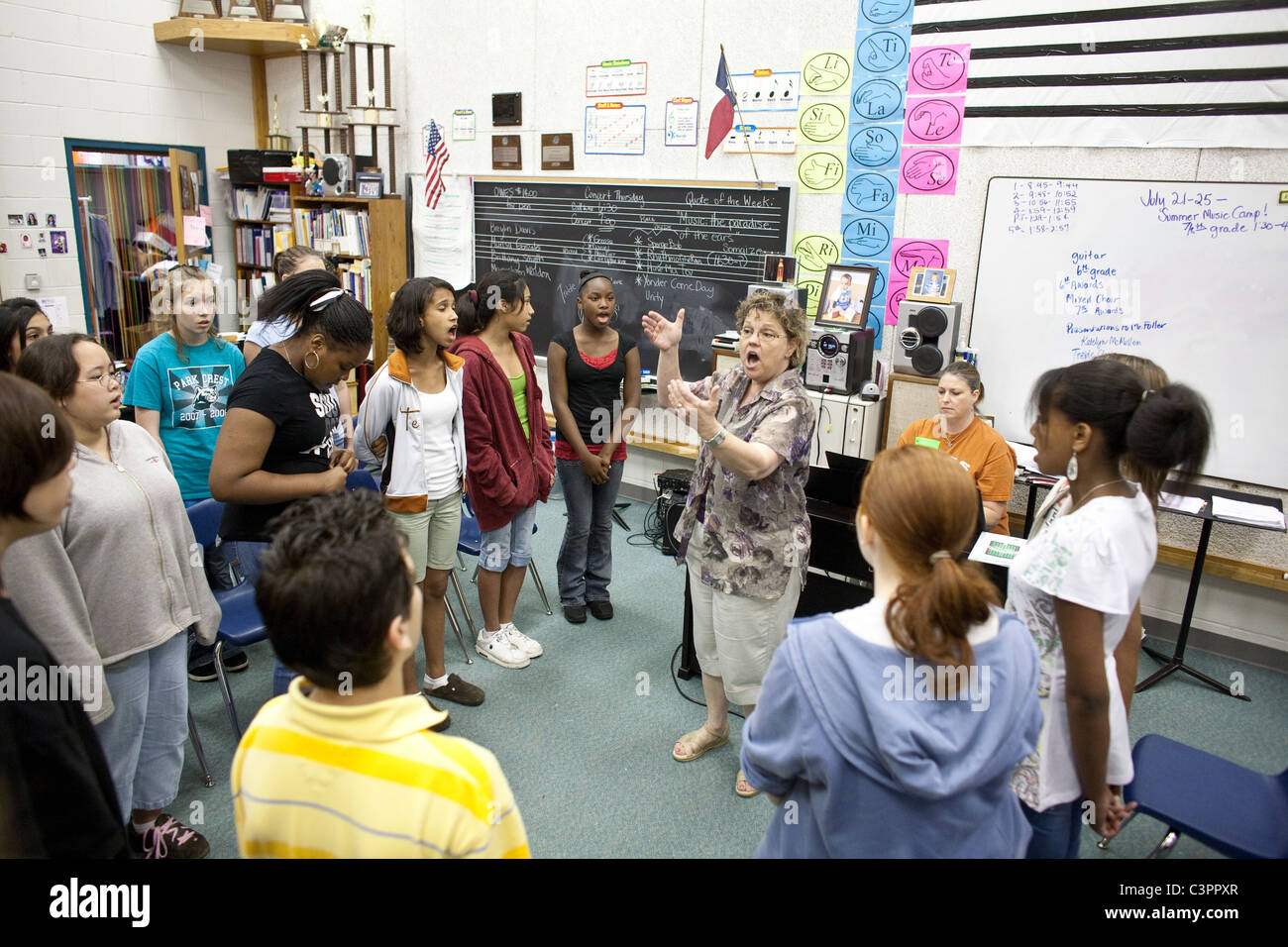 Anglo female music teacher conducts rehearsal for upcoming choir concert in classroom at middle school in Pflugerville Texas USA Stock Photo