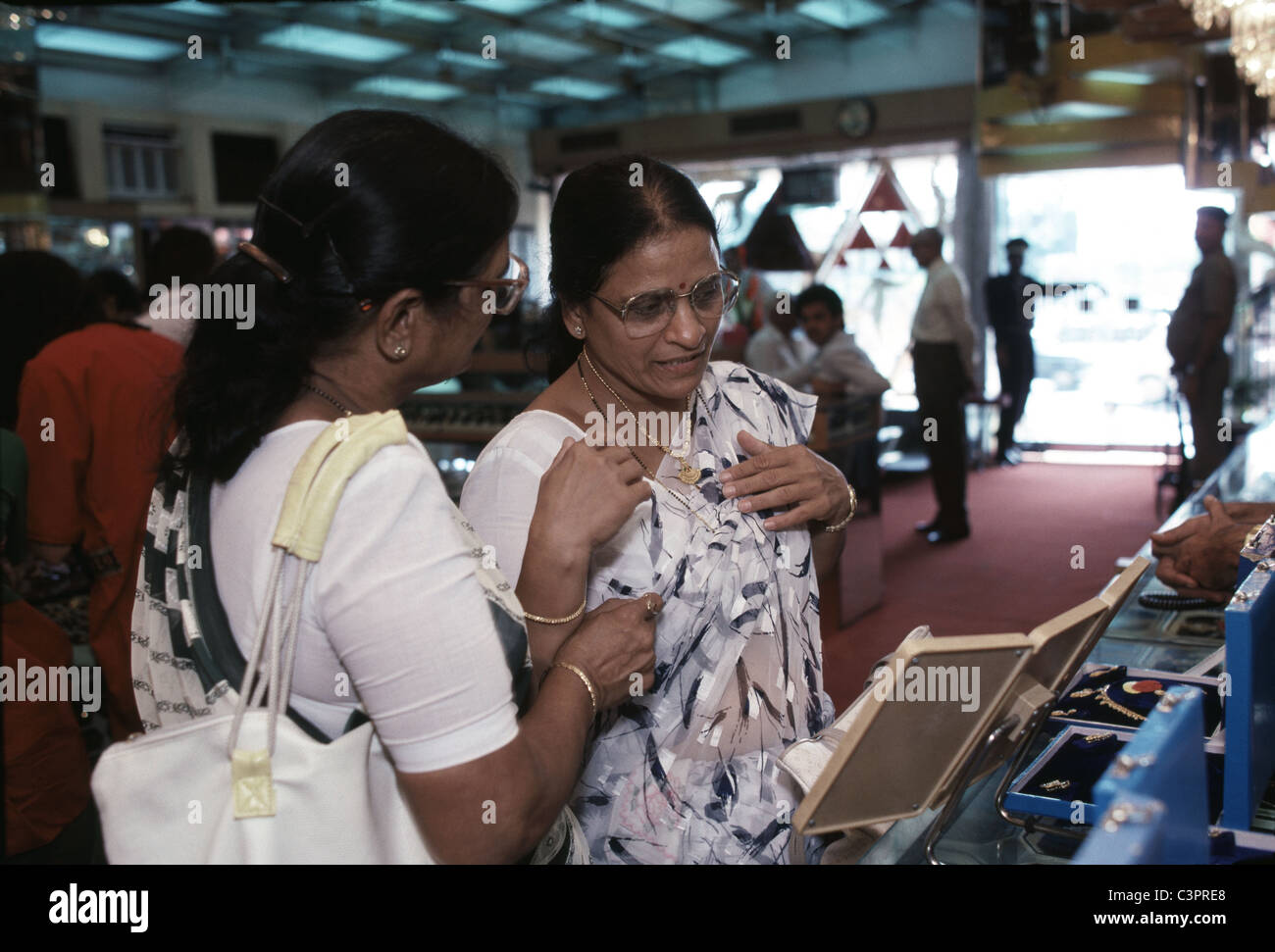 Two women inspect a gold necklace at a New Delhi, India gold shop. Stock Photo