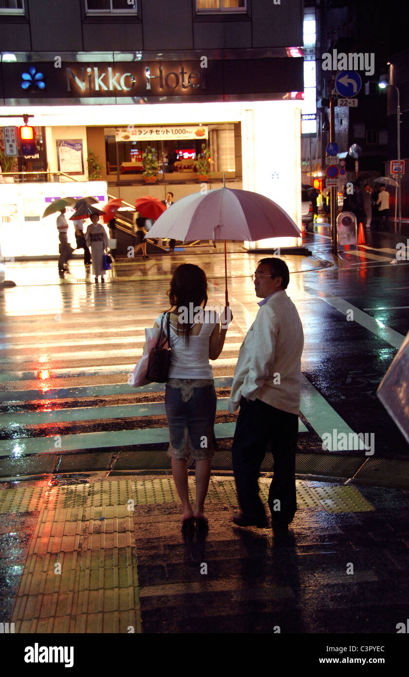 Japanese couple wait for taxi on rainy night time Tokyo street TIME WALK JAPAN ID TAG