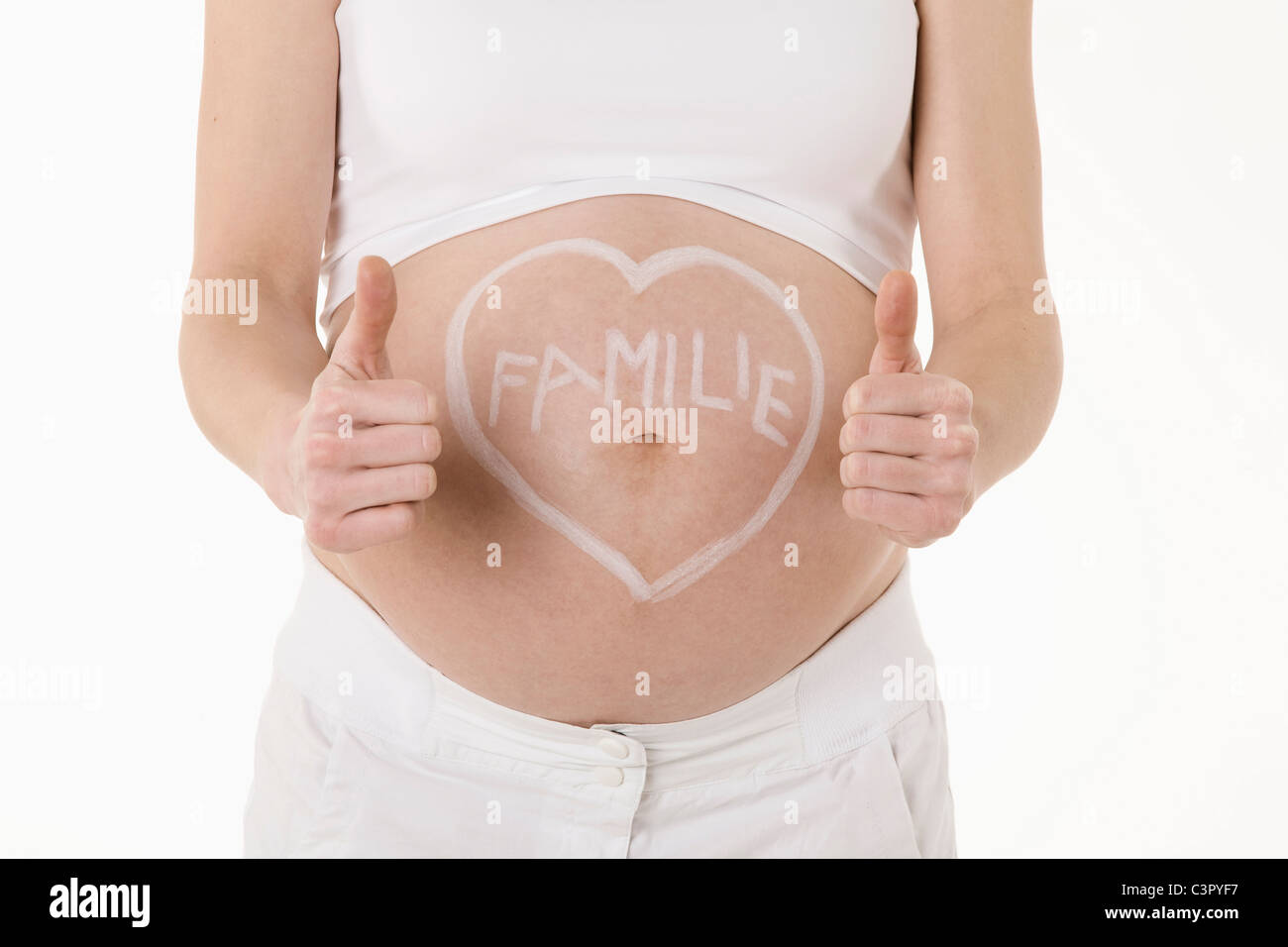Heart shape drawn on pregnant woman's belly with text, showing thumbs up sign Stock Photo