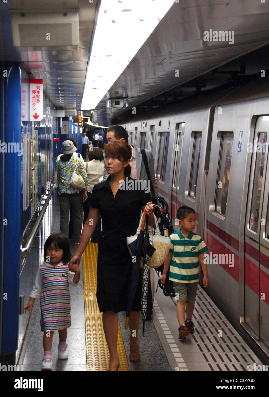 Japanese woman with two children leaving a Tokyo subway train, Tokyo Japan Stock Photo