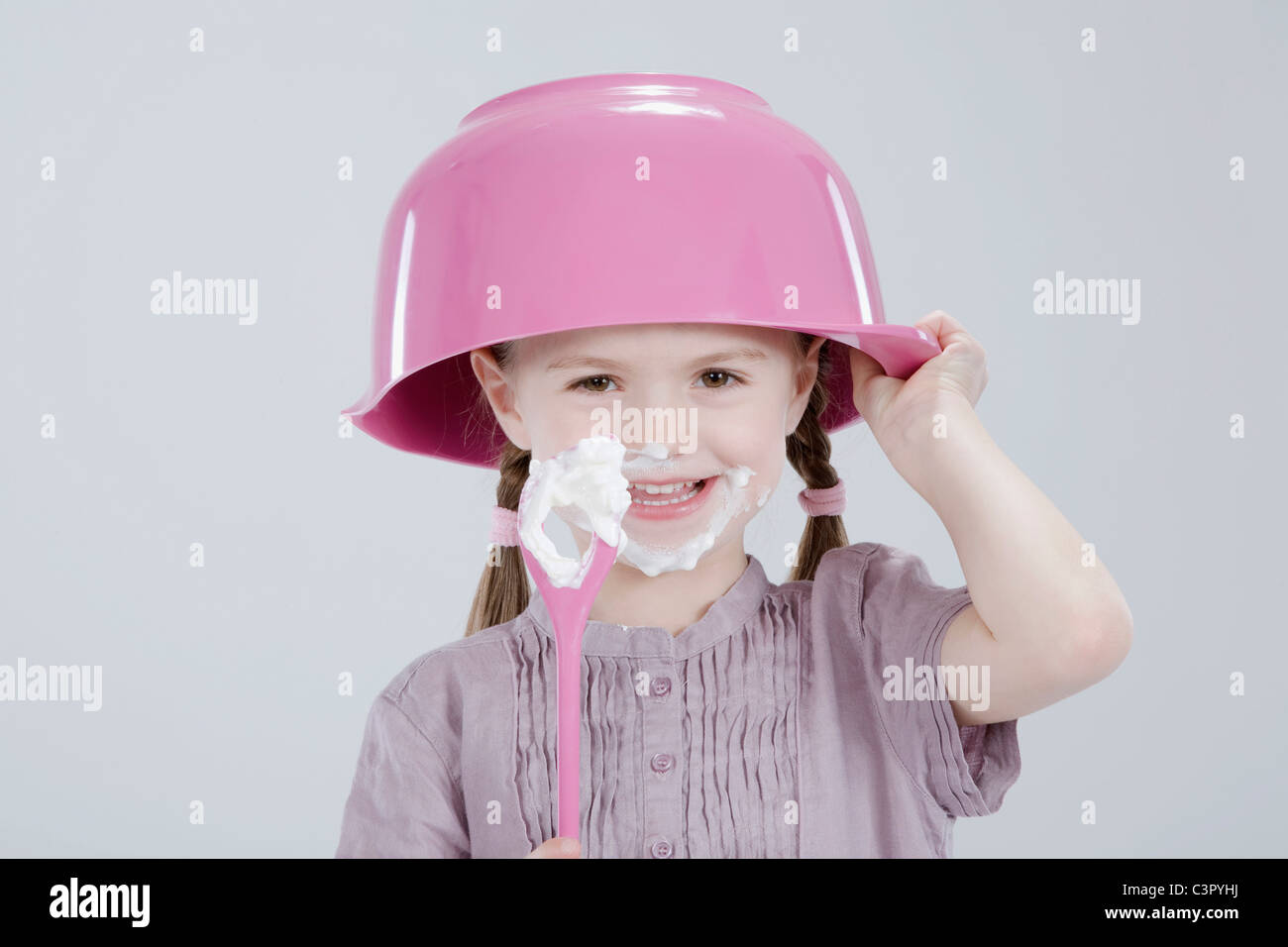 Girl (4-5) with messy  face wearing bowl hat and spoon Stock Photo