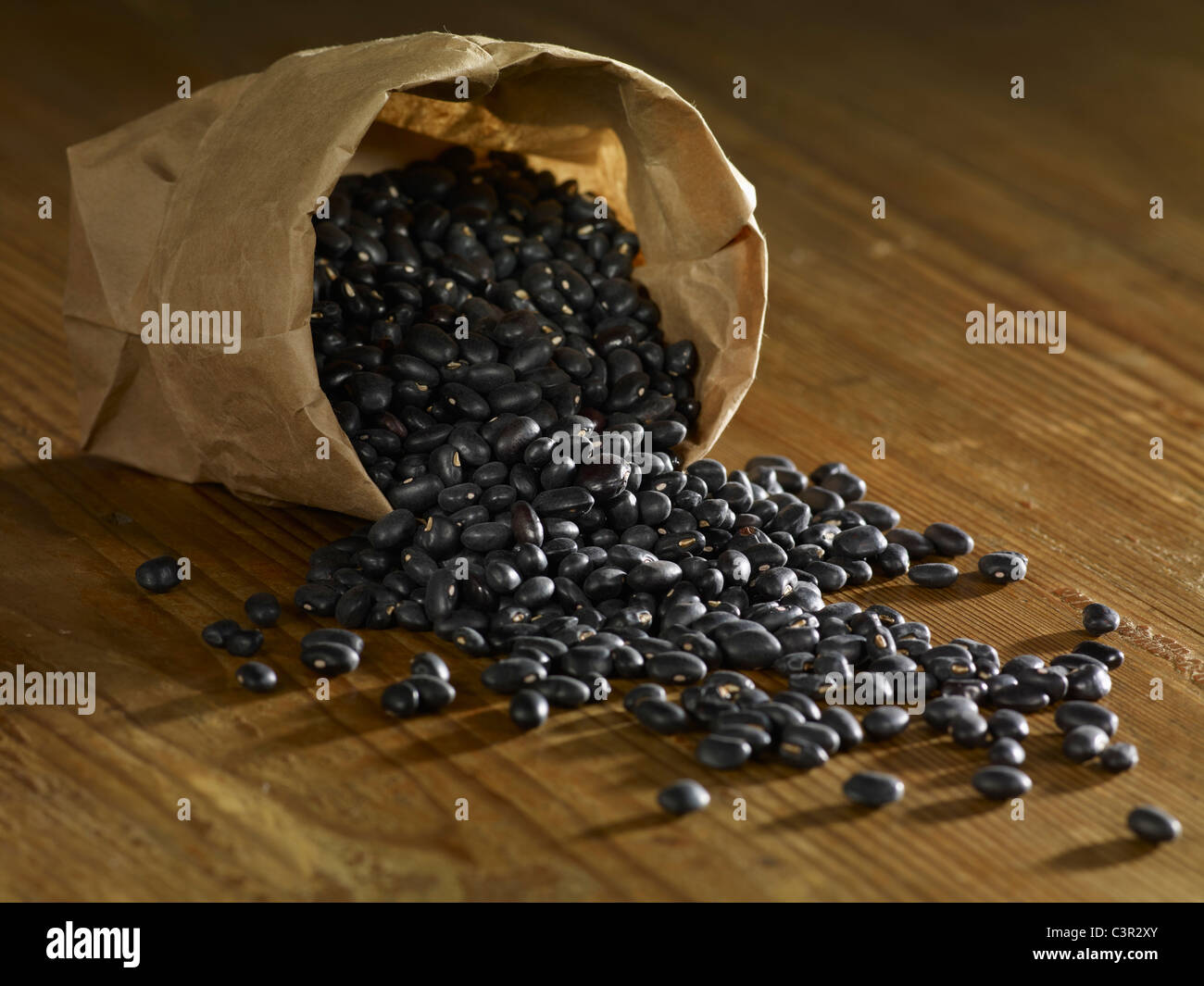 Bag of black beans spilled on wooden surface Stock Photo Alamy