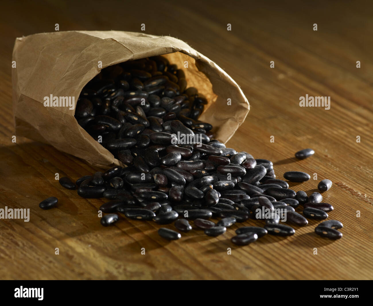 Bag of black beans spilled on wooden surface Stock Photo Alamy