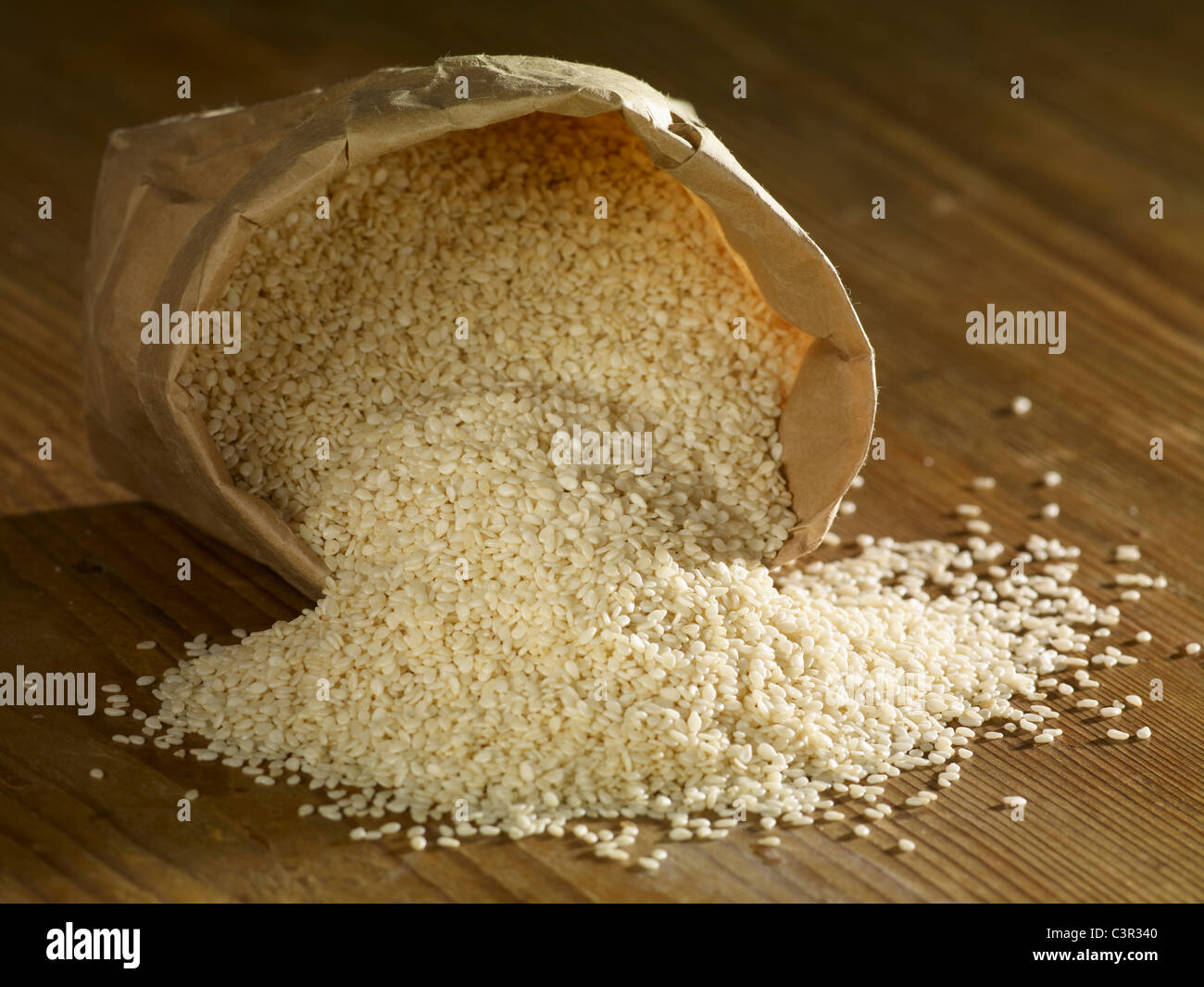 Split sesame seeds spilling on wooden surface Stock Photo Alamy