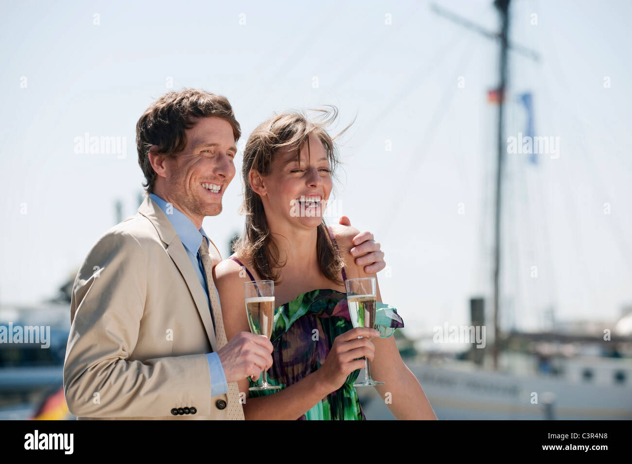 Germany, Hamburg, Couple looking away and drinking champagne, smiling Stock Photo