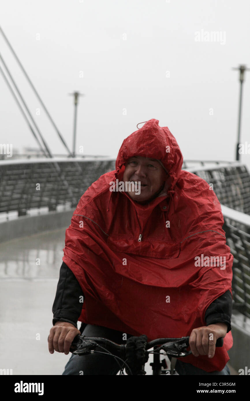 Man in raincoat cycling Stock Photo