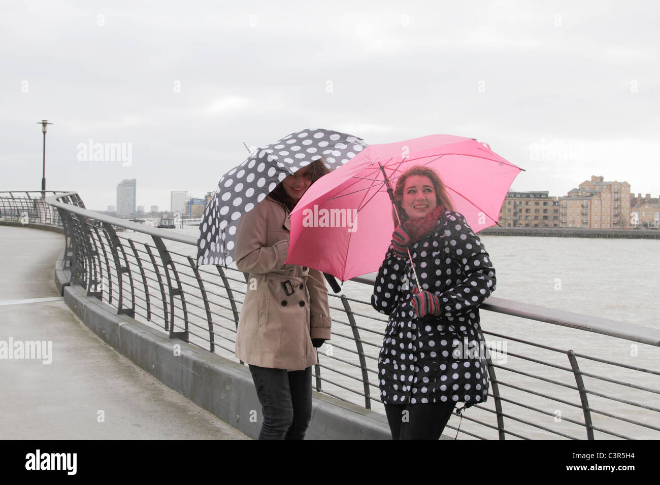 2 yougn women with umbrellas by river Stock Photo