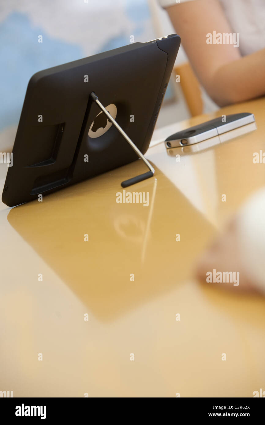 iPad 1 and iPhone 4 on a desk during a business meeting. Stock Photo