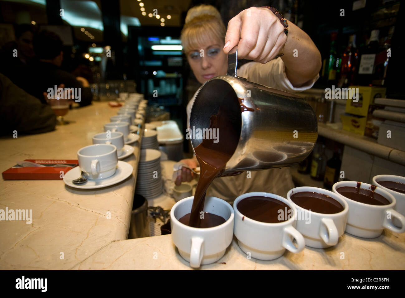 6:34 AM: A waitress serves hot chocolate for traditional Spanish breakfast 'chocolate con churros' at San Gines, in Madrid. Stock Photo