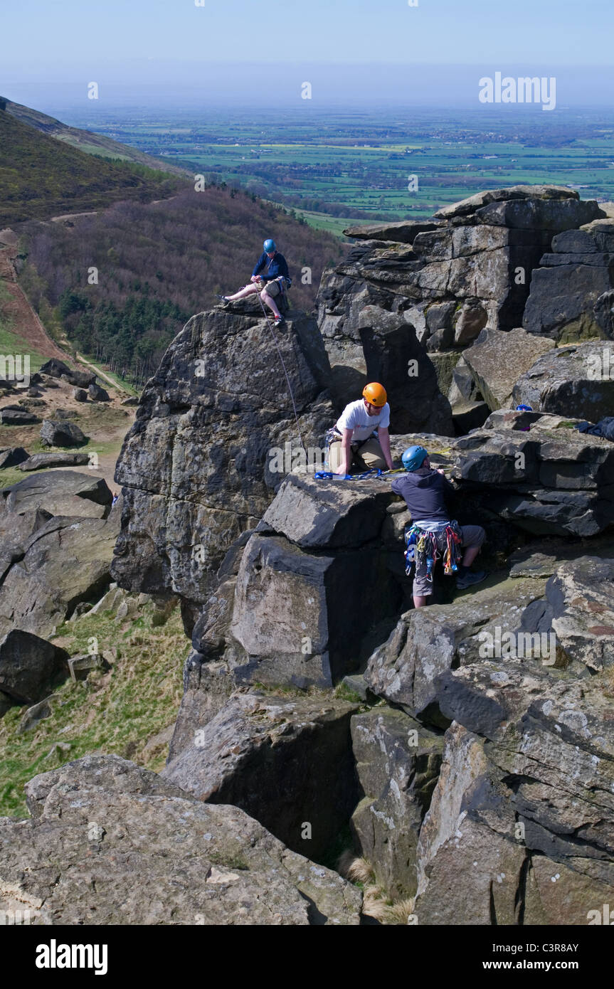 3 rock climbers on the Wainstones, Hasty Bank, the Cleveland Way, overlooking Broughton Plantation and Stokesley Plain, N Yorks Stock Photo