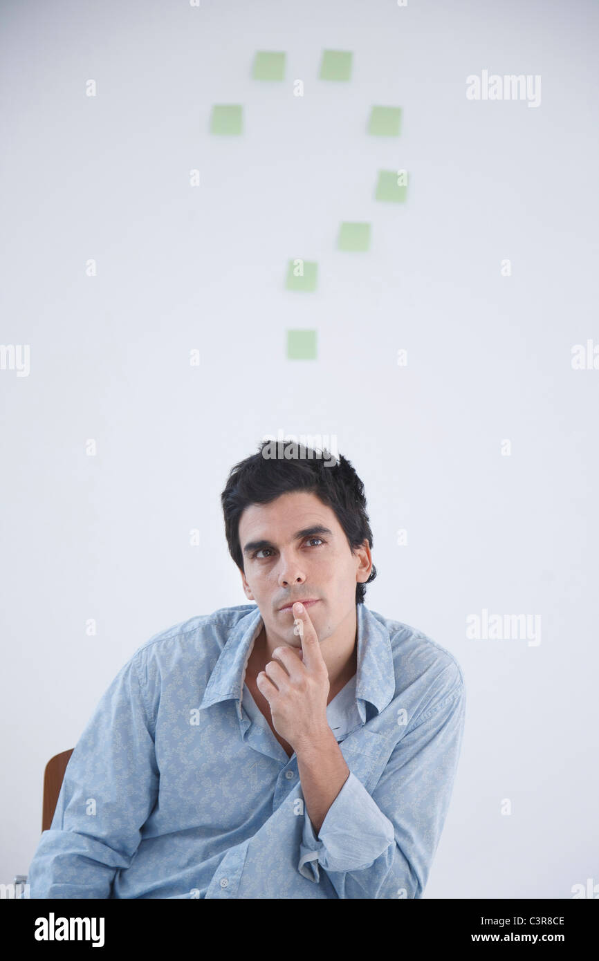 Man thinking with post-it note question makr behind him Stock Photo