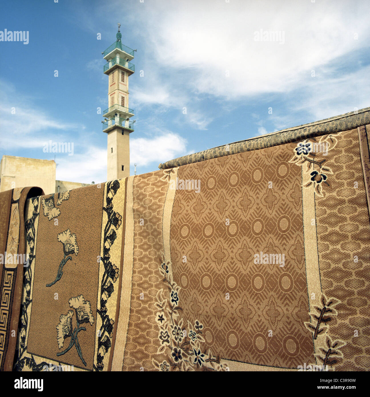 Jordan, Amman, Traditional carpets with minaret in background Stock