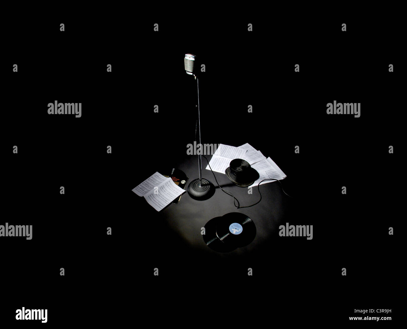 old Mic stand with music sheets and top hat and records on the floor Stock Photo