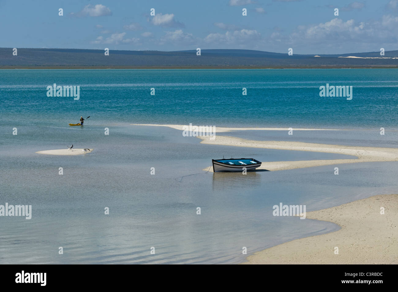 Boy in a canoe and a boat in Langebaan lagoon in Churchhaven, West Coast National Park South Africa Stock Photo