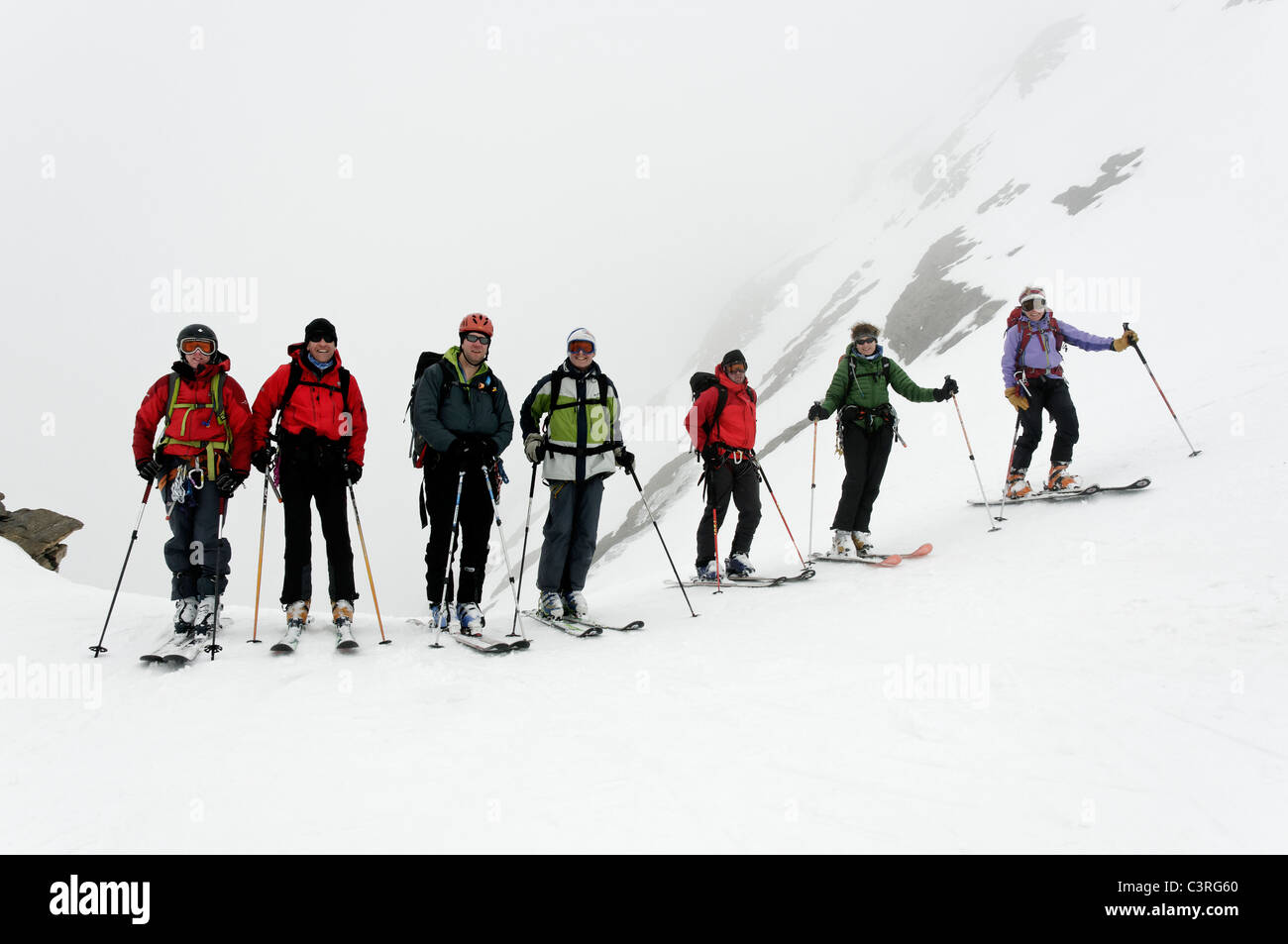 A group of ski tourers taking a break on a misty col in the Gran Paradiso National Park, Italy. Stock Photo
