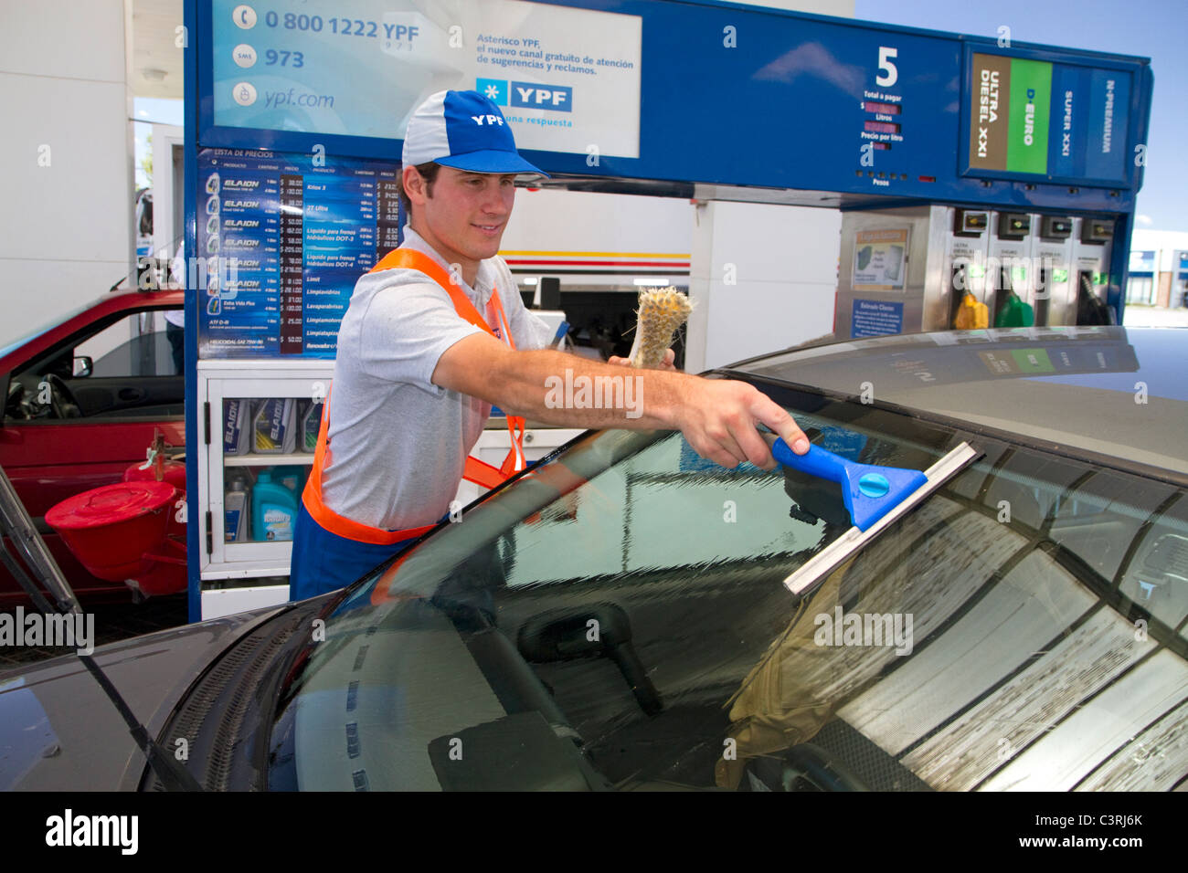 Gas station attendant washing an automobile windshield in Argentina. Stock Photo