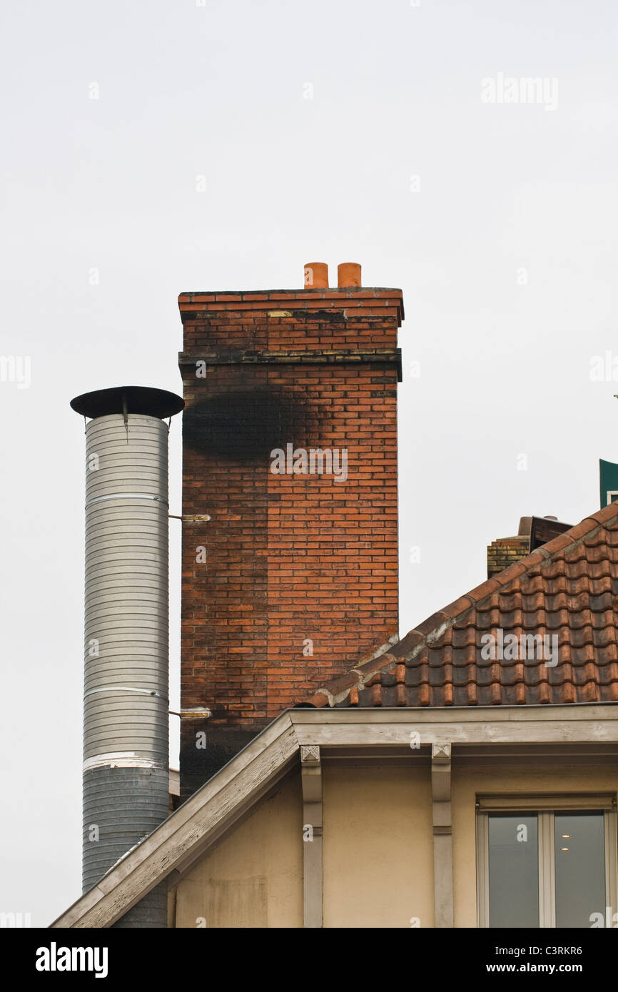 red brick chimney and metal chimney on tiled roof Stock Photo - Alamy