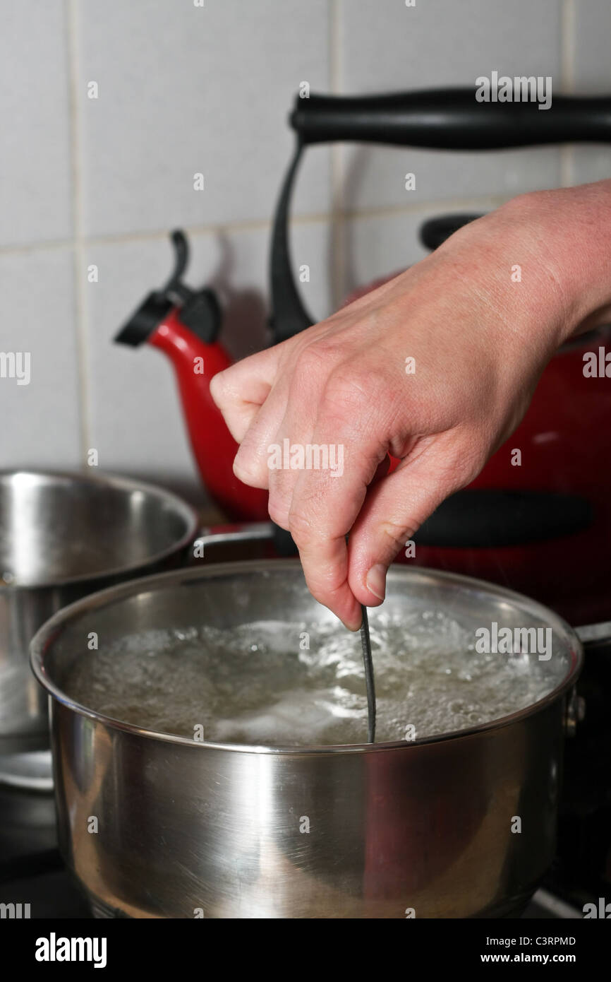 Hand stirring a pan of boiling water Stock Photo