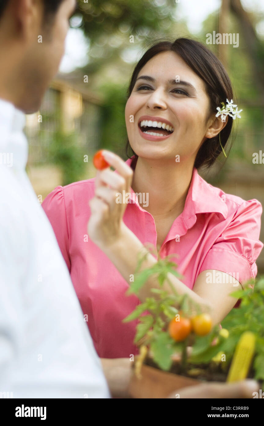 Hispanic woman feeding tomato to husband Stock Photo