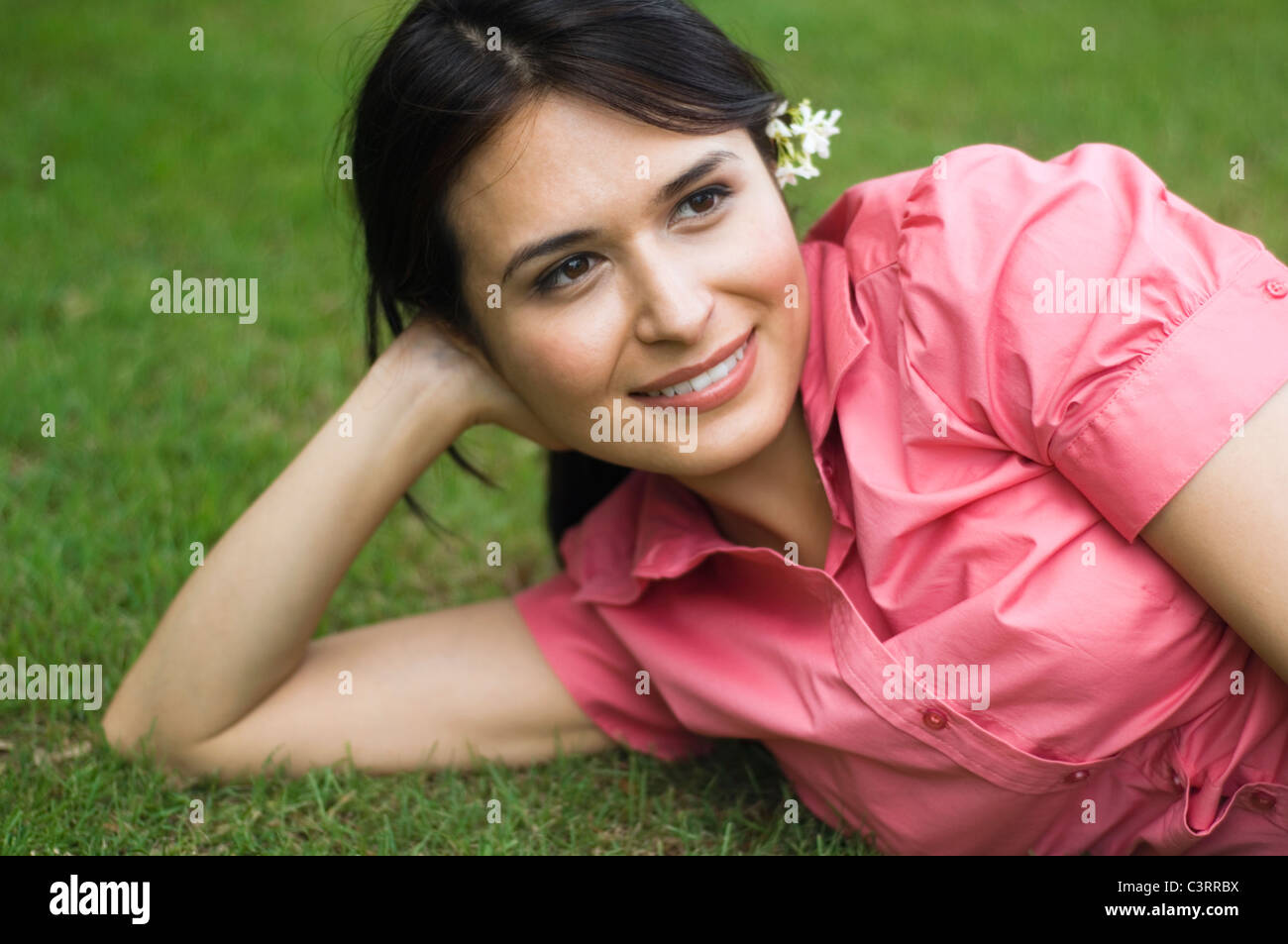Hispanic woman laying in grass Stock Photo