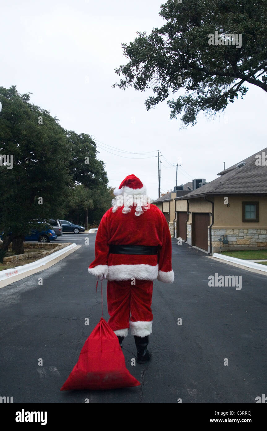 Santa dragging sack down road Stock Photo