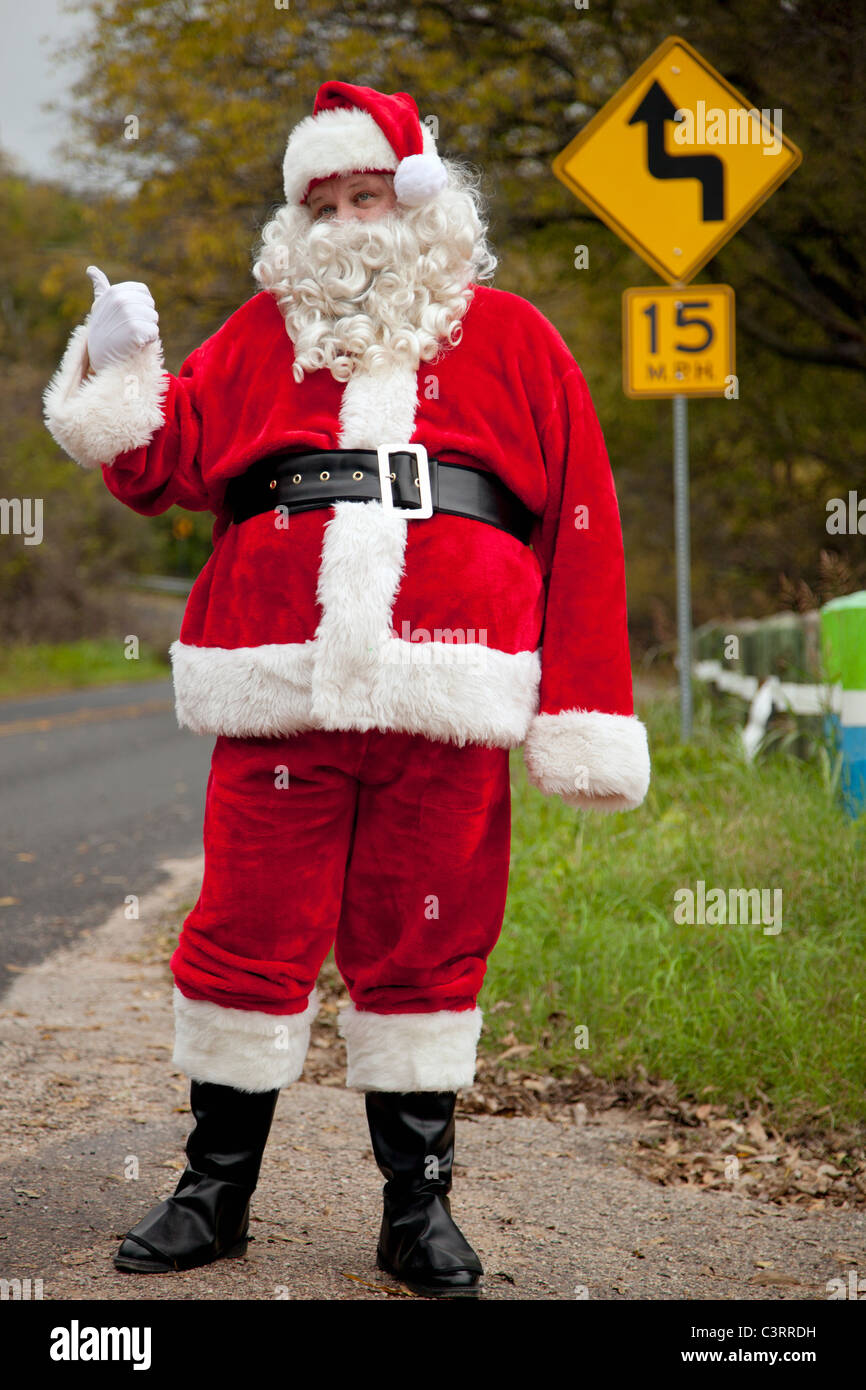 Santa hitchhiking at roadside Stock Photo