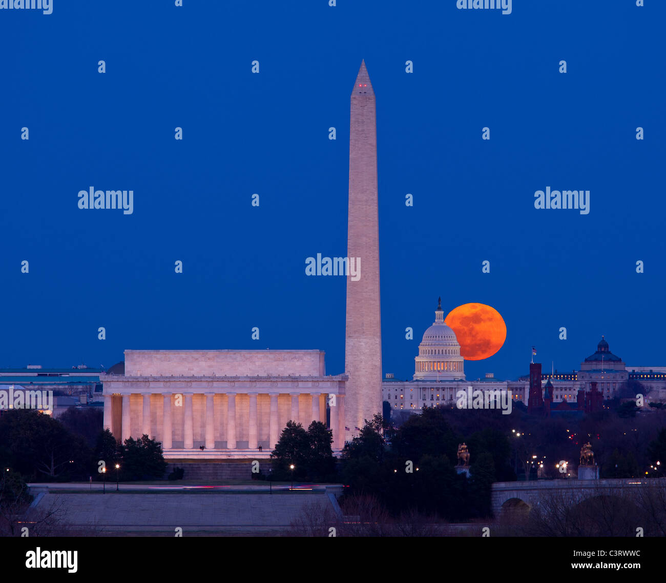 Large full moon rises through the haze over the Capitol building in Washington DC with Lincoln Memorial and Washington Monument aligned Stock Photo