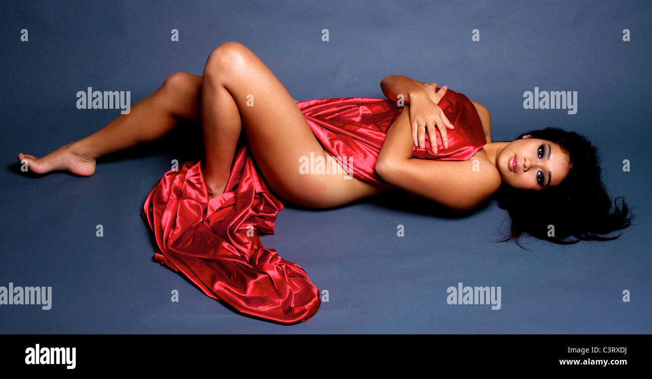 A girl lies draped with red satin Stock Photo