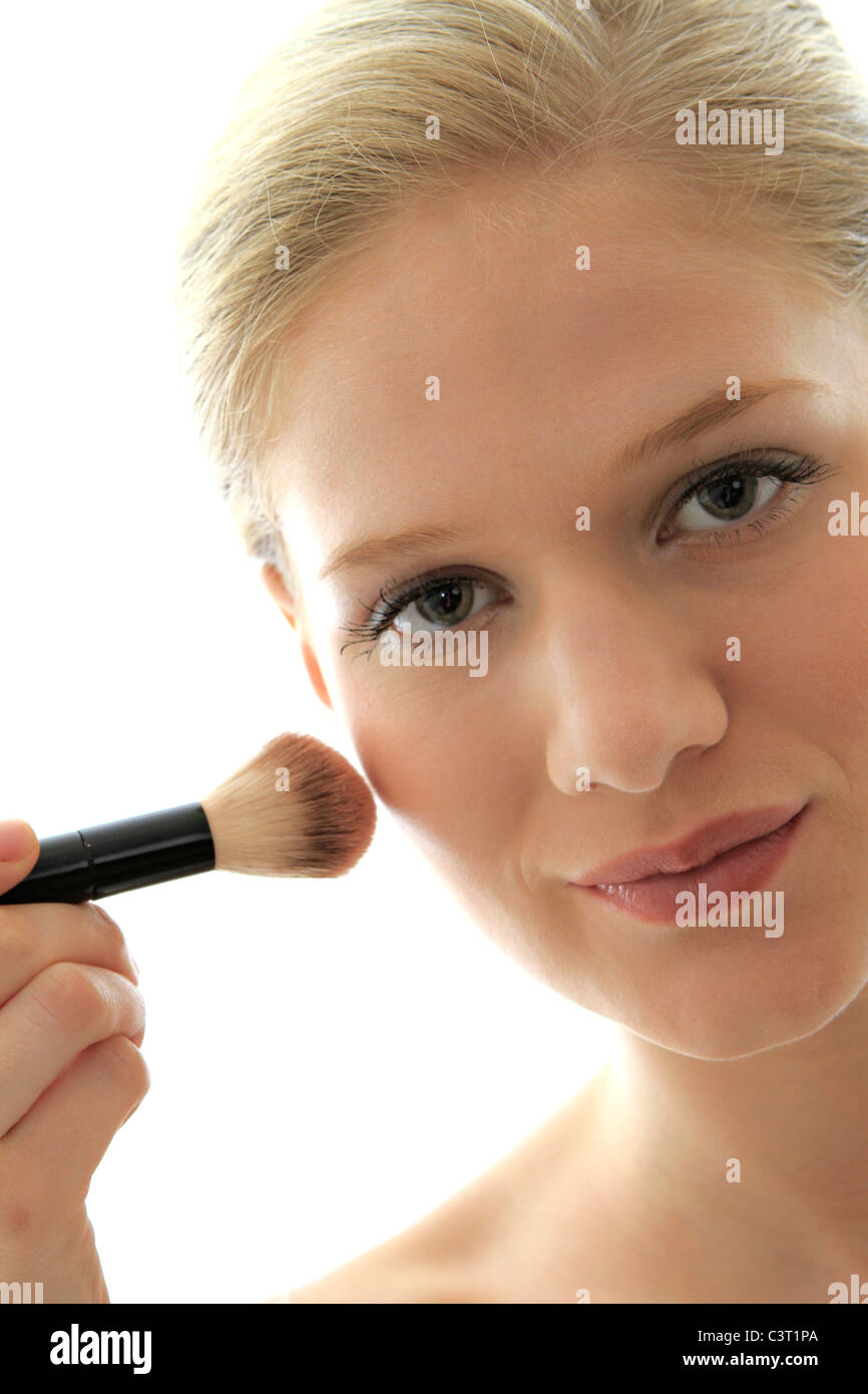 Portrait of attractive young adult woman applying blusher Stock Photo