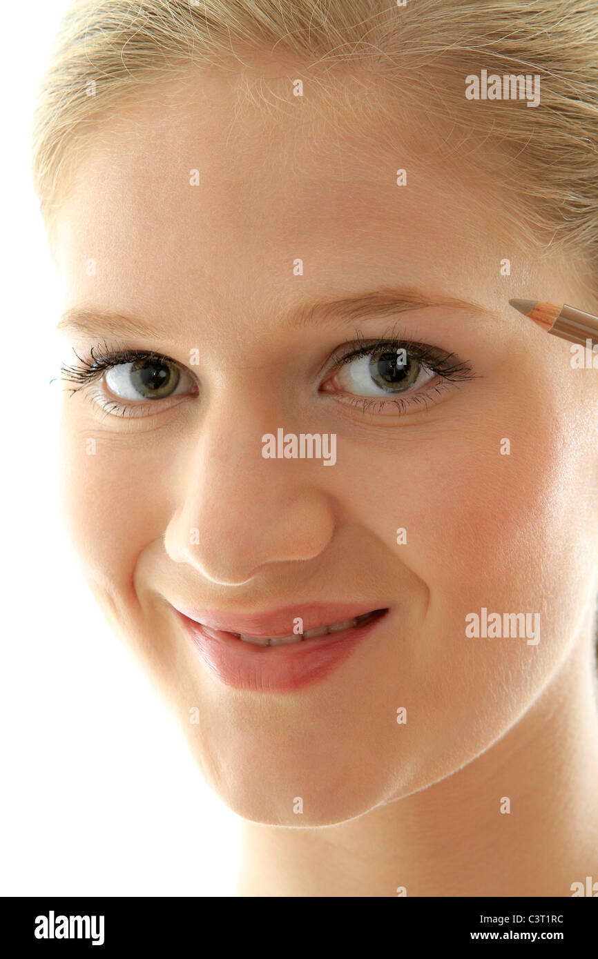 Closeup portrait of a pretty young girl applying eyeliner Stock Photo